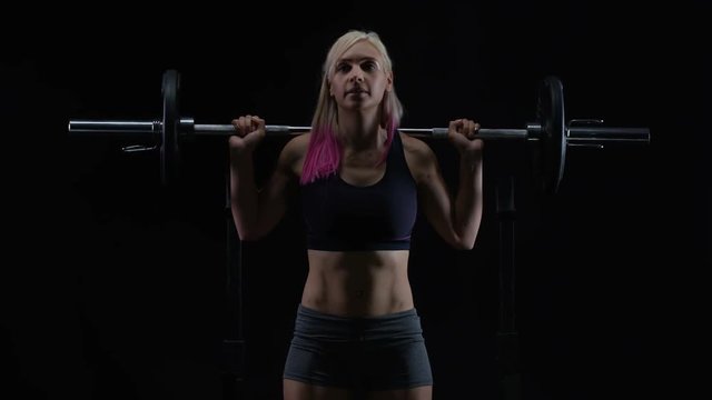  Fit young woman weight training, doing squats with barbell