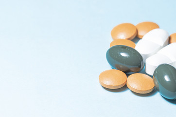 drugs and pills, group of pills over a pale blue background with copys space on the left. pharmaceutical. disease. cure. medicine