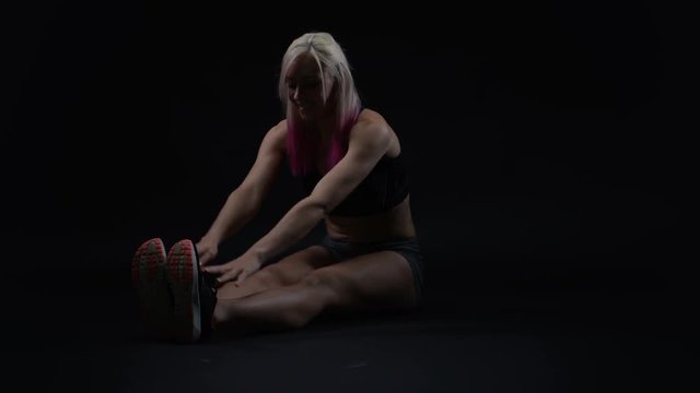  Fit young woman with athletic physique doing stretches to improve flexibility