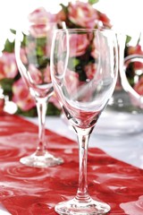 Table set with wine glasses, bouquet of roses in background