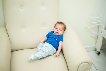 Blue-eyed baby boy sitting on the armchair - Relaxing