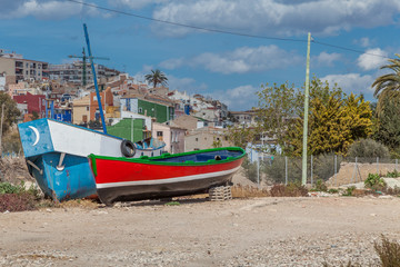 a red boat on a beach with blue sky and palm trees