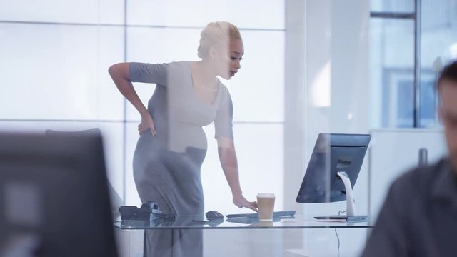  Pregnant businesswoman standing to work at her desk in modern office