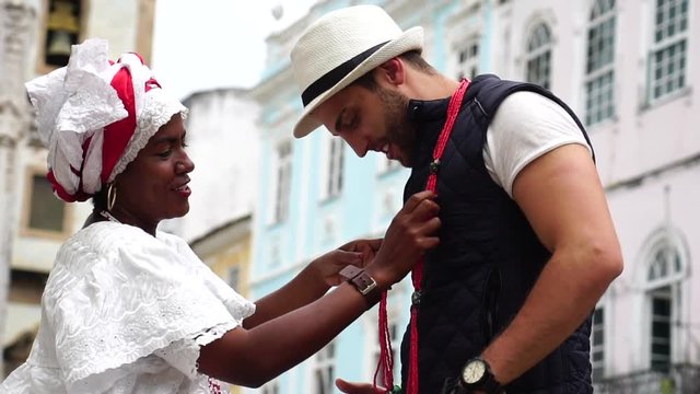 Brazilian Woman Giving Her Necklace to Tourist in Salvador, Bahia