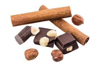 Pieces of bitter dark chocolate cubes with hazelnut and cinnamon stick isolated on white background