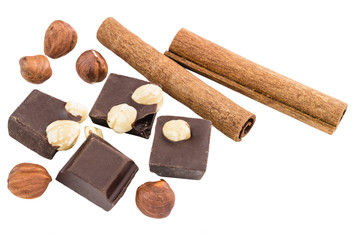 Pieces of bitter dark chocolate cubes with hazelnut and cinnamon stick isolated on white background