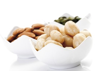 Assorted nuts in porcelain bowls, macadamia kernels, pistachio kernels and almond kernels