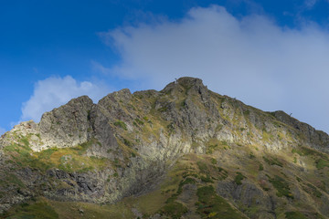 the top of the mountain on the background of the autumn sky and clouds