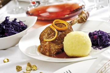 Goose-leg, red cabbage, potato dumpling on a festively decorated table