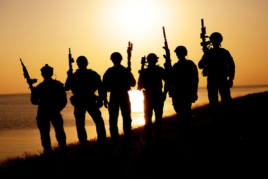 Army soldiers with rifles orange sunset silhouette
