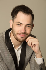 portrait of a smiling stylish man with an unshaven face, in a suit on a light background