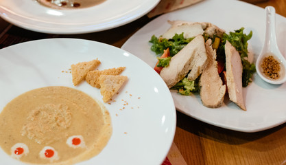 Soup is served on the table. Time for lunch. Chicken salad in the background