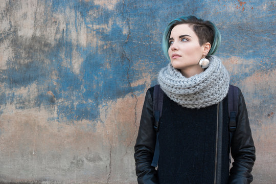 Sad Young Woman With Blue Hair Wearing Knited Scarf On Background Of Old Blue Wall 