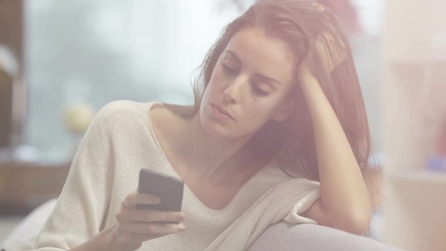  Portrait unhappy or annoyed woman texting on smartphone at home