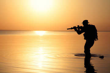 Fototapeta na wymiar Army soldier with rifle orange sunset silhouette