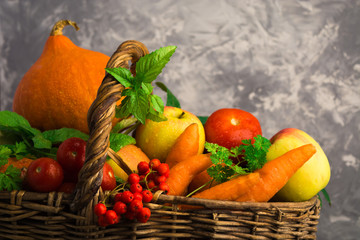 Different fruits and vegetables in wicker basket on grey background