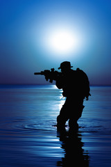 Fototapeta na wymiar Army soldier with rifle night moon silhouette under cover of darkness in action during raid crossing river in the water. Covert diversionary operation