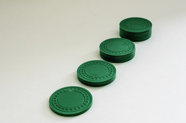 Horizontal view of an angled row of stacked green poker chips