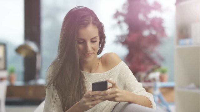  Portrait attractive smiling woman relaxing at home, looking at smartphone