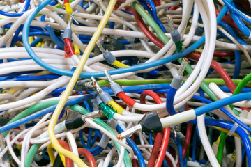 The bunch of electric wires of different colors are very much intertwined. On tangled wires is wire-end ferrules and markings. Chaos, confusion, tangle.