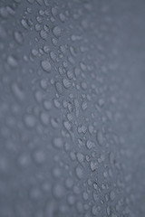 Regentropfen auf einer grauen Zeltplane im Detail aufgenommen