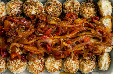 Small round meat balls with a sauce of tomatoes, onions and peppers close-up. Background.