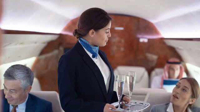  Portrait stewardess on private plane serving champagne to business travelers