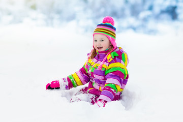 Fototapeta na wymiar Child playing with snow in winter. Kids outdoors.