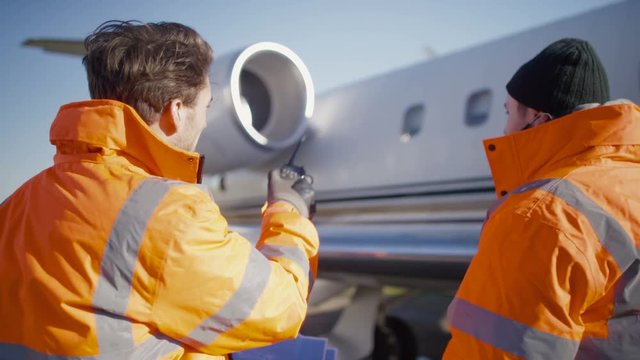  Aircraft engineers with blueprint checking over plane on the runway