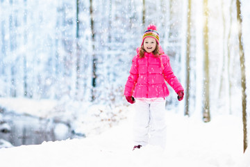 Child playing with snow in winter. Kids outdoors.