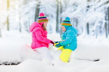 Fototapeta na wymiar Kids playing in snow. Children play outdoors in winter snowfall.