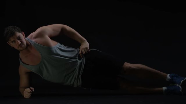  Fit young man with muscular physique doing exercises to improve core strength