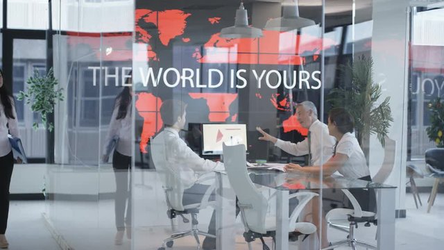  Business team in a meeting, looking at world map with motivational slogan