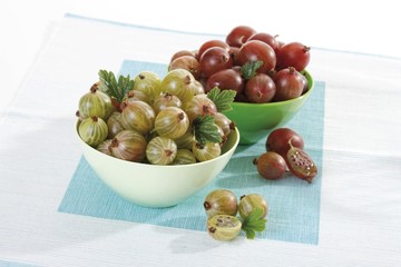 Red and green gooseberries in bowls