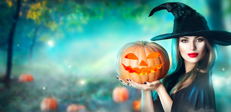 Halloween Witch With A Carved Pumpkin And Magic Lights In A Dark Forest