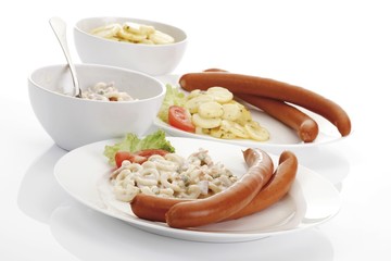 Two plates of wieners with potato - and pasta salad