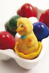 Marzipan chick and painted eggs in a porcelain egg carton