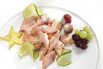 Salmon garnished with fruit: star fruit (carambola), limes, grapes and lychees