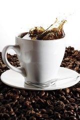 Spilling over cup of coffee on coffee beans