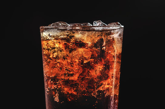 close up ice cola in glass and bubble soda on black background