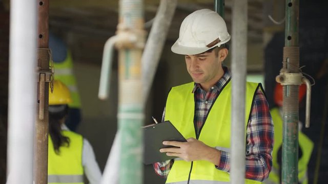  Portrait smiling worker at construction site writing notes on clipboard