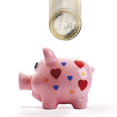 Euro coin falling into pink piggy bank (composing shot)