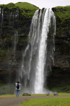 Female tourist taking photos at the Seljalandsfoss-waterfall in Iceland