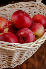 Red apples in basket on wooden background