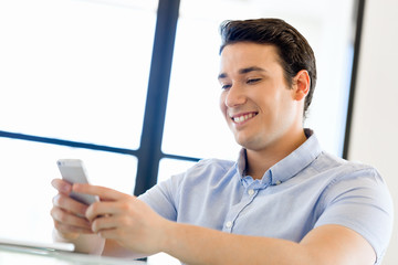 Confident young man in smart casual wear holding phone