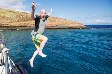 Bald man jumping into the ocean