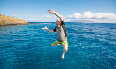Bald man jumping into the ocean