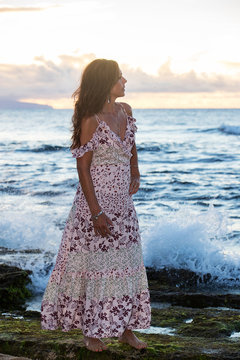 Beautiful woman wearing prettyy dress at the ocean during sunset