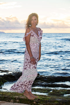 Beautiful woman wearing prettyy dress at the ocean during sunset