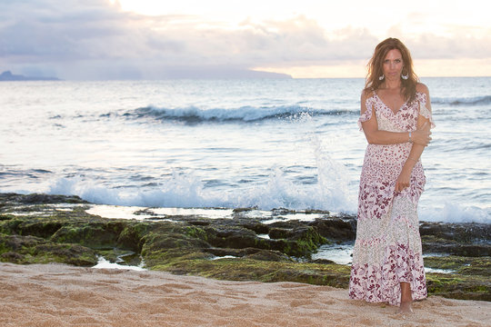 Beautiful woman wearing prettyy dress at the ocean during sunset
